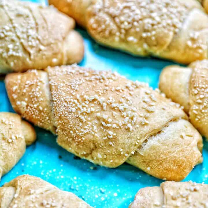 square photo of Filipino Spanish bread closeup on a bright blue background.