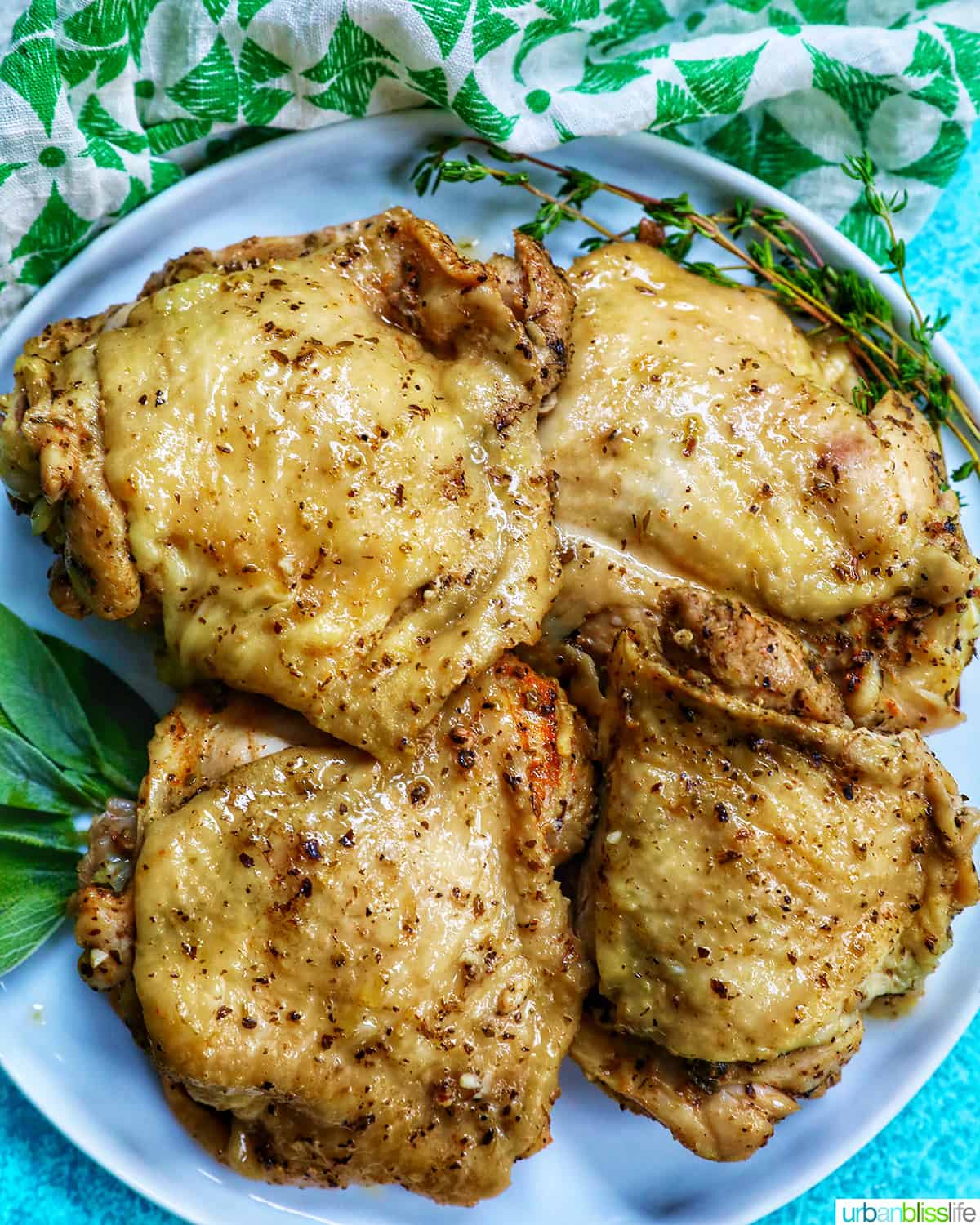 four instant pot chicken thighs on a white plate with green napkin and blue background.