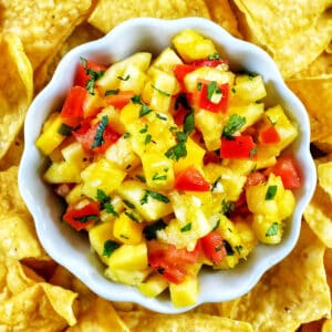 Pineapple mango salsa in a bowl surrounded by tortilla chips.