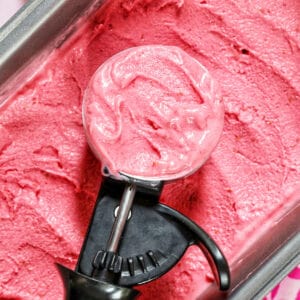 raspberry sherbet in a scoop over a tray of sherbet.