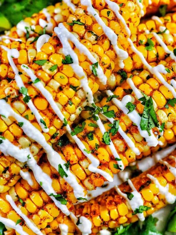 closeup photo of air fryer corn ribs stacked on top of one another with drizzled mayo and chopped cilantro.