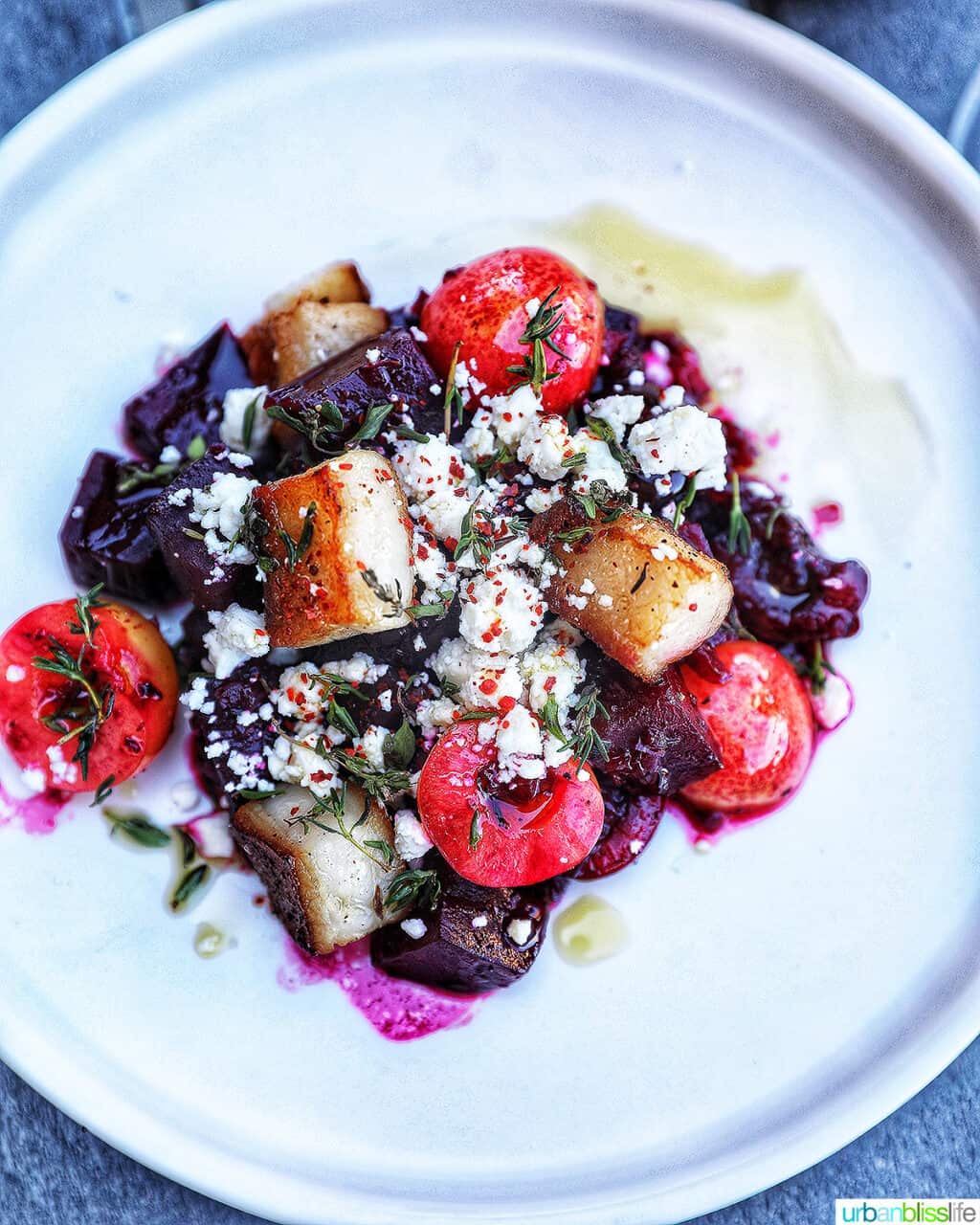 beet agrodolce with cherries and pork belly on a white plate.