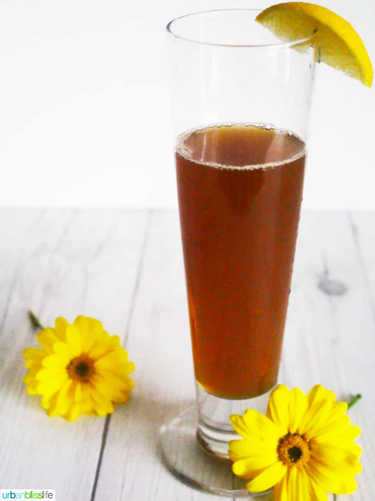 iced tea and beer cocktail with yellow flowers and garnished with lemon wedge.
