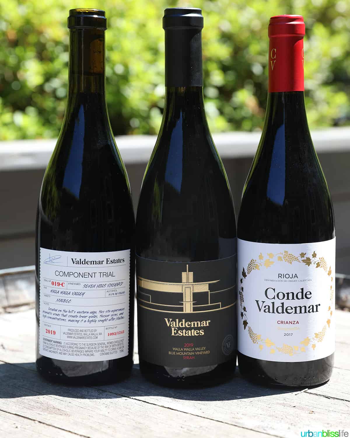 three bottles of wine from Valdemar Estates lined up on top of a wine barrel on a sunny day.