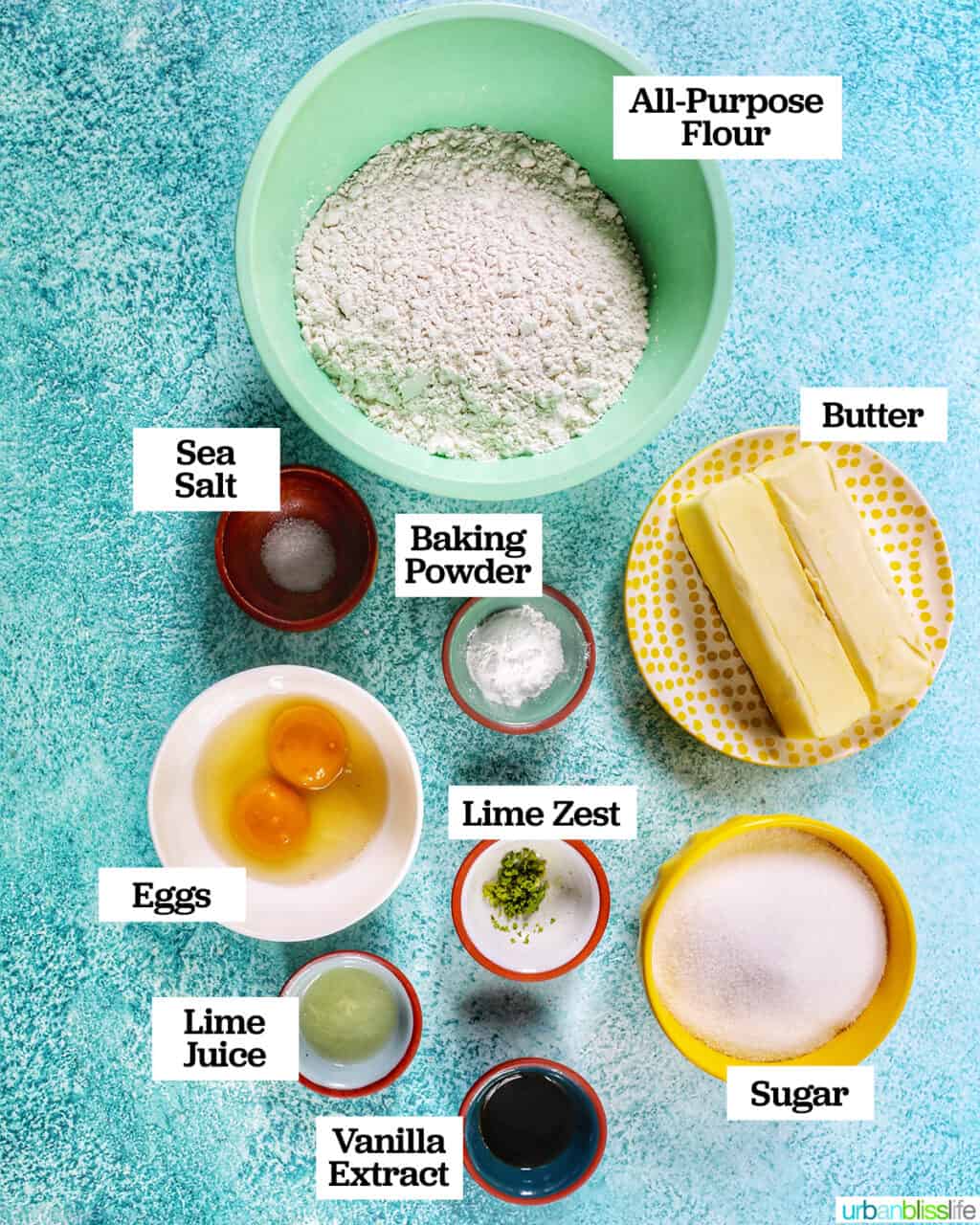 several bowls of ingredients to bake key lime sugar cookies on a blue background.