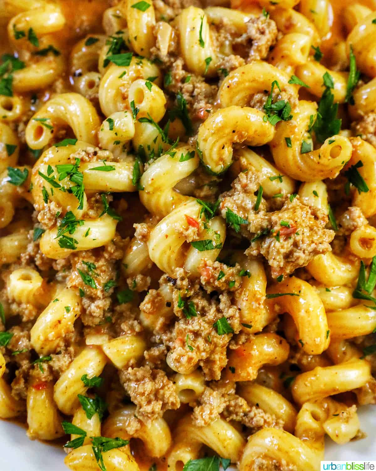 closeup of bowl of dairy free one pot cheeseburger pasta with ground turkey and chopped parsley.