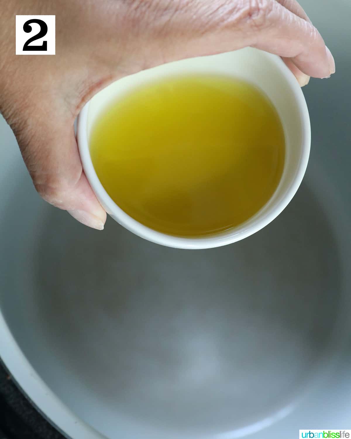 hand adding olive oil to the inside pot of a ninja foodi or instant pot.