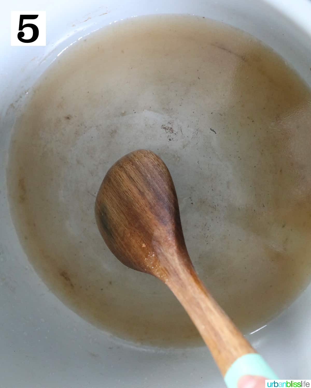 wooden spoon scraping up browned bits at the bottom of a ninja foodi pressure cooker or instant pot.
