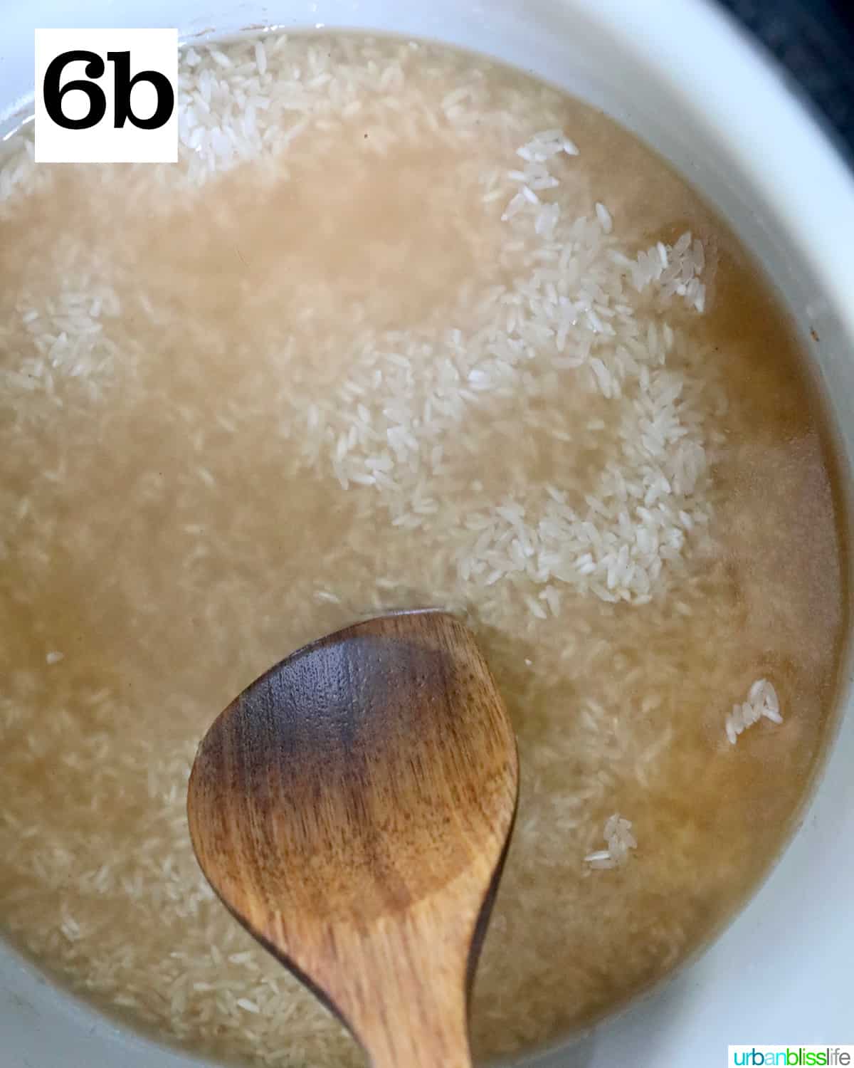 wooden spoon gently pushing down rice into broth in an instant pot.