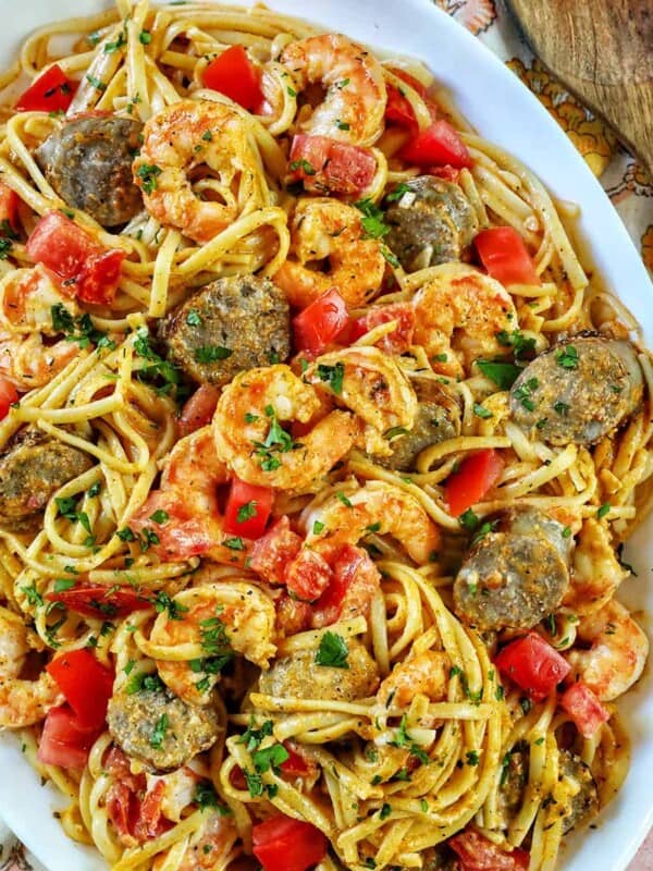 large serving platter of shrimp and sausage pasta with wooden spoon.
