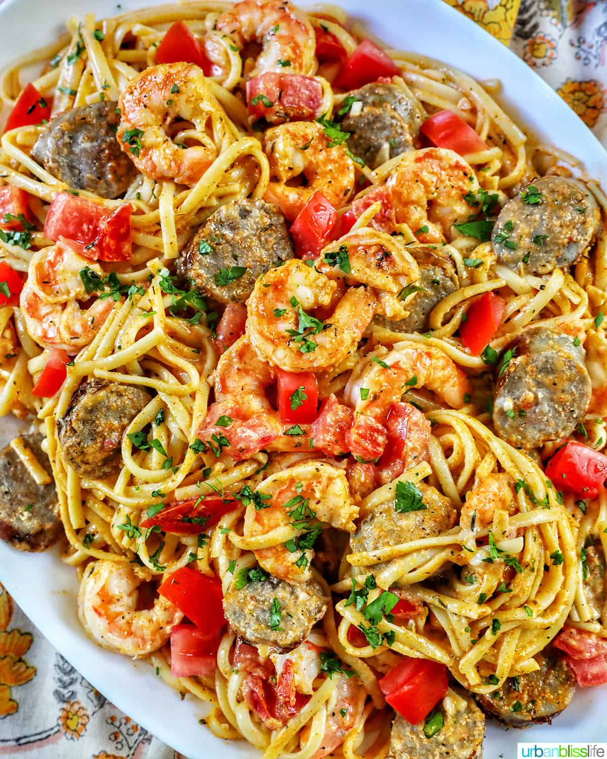 big platter of shrimp and sausage pasta with tomatoes and herbs.