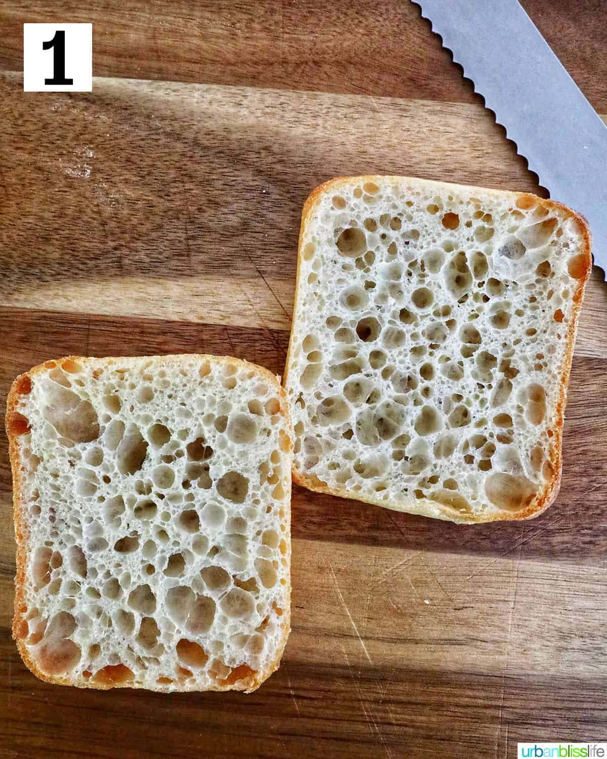 ciabatta bread cut in half on top of a cutting board with knife at an angle.