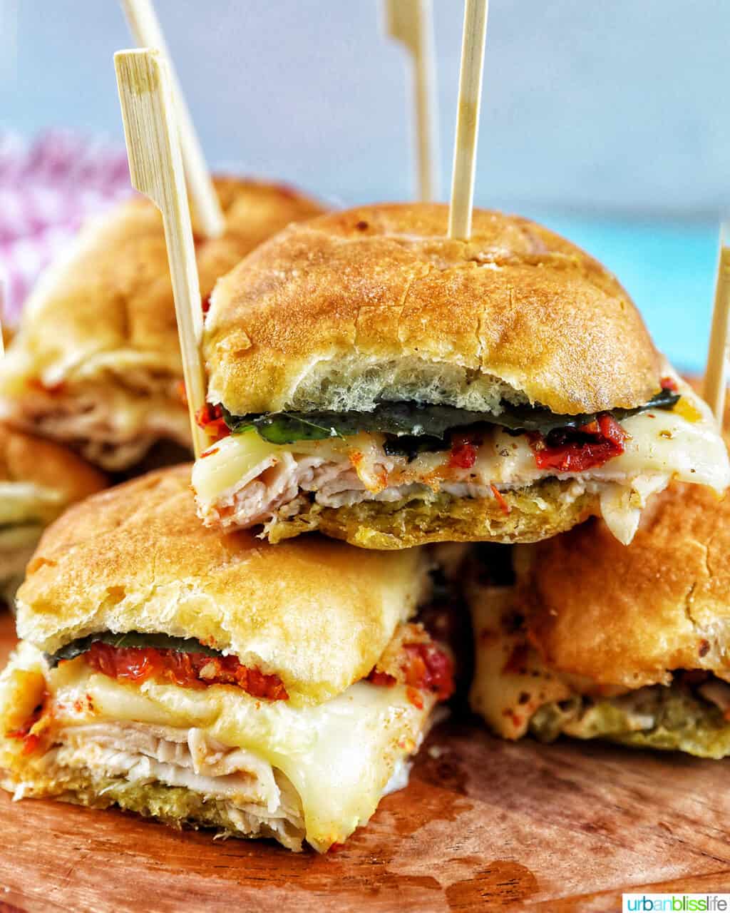 turkey pesto sandwich sliders with food picks for game day appetizers, stacked on top of one another.