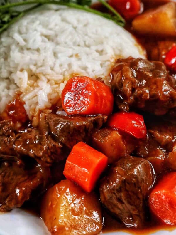 bowl of Filipino beef mechado with white rice and parsley.