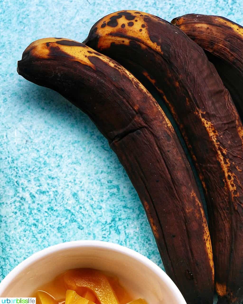 three overripe bananas on a bright blue table.