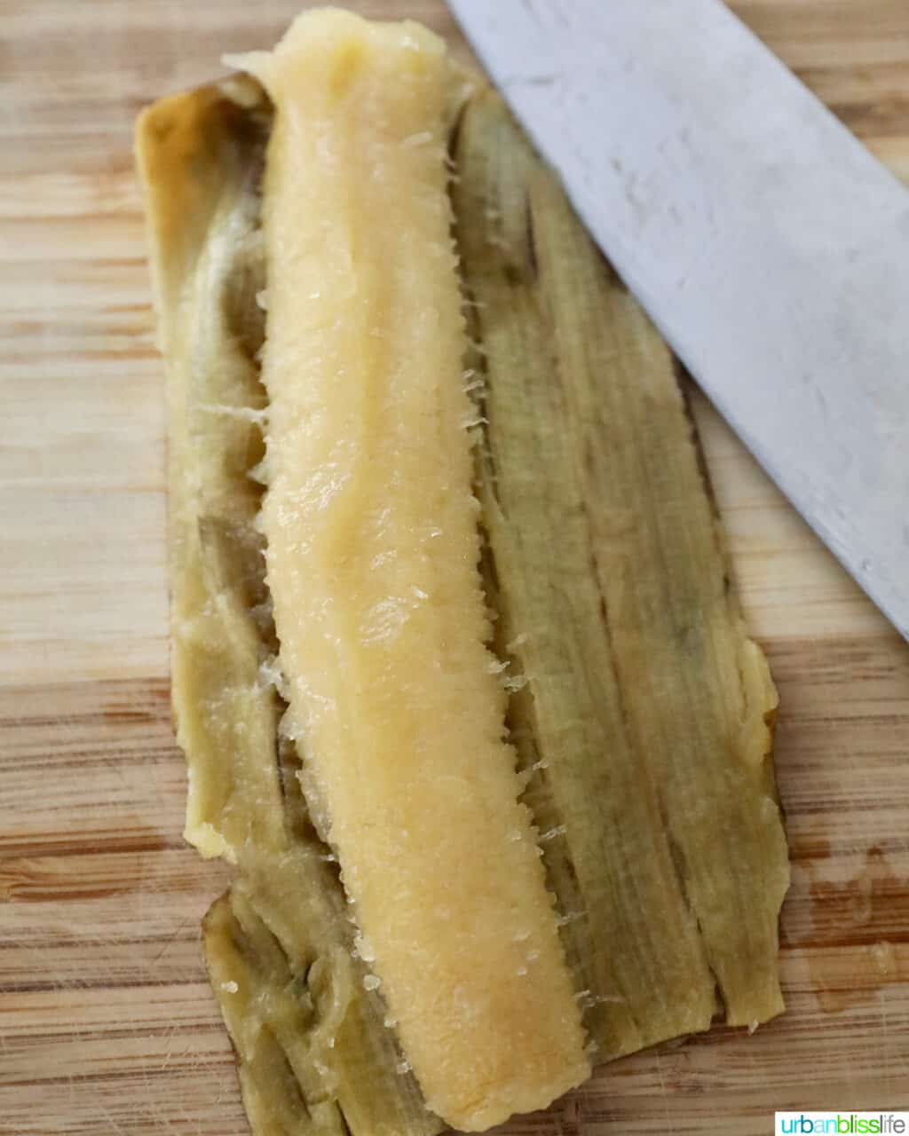 peeled ripe banana on a cutting board with a knife.