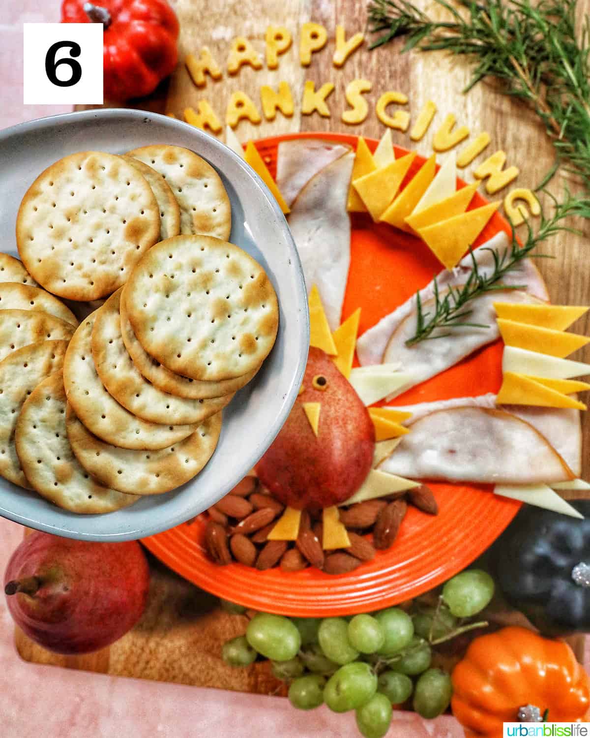 plate of crackers over a thanksgiving charcuterie board with meat, cheese, fruit.