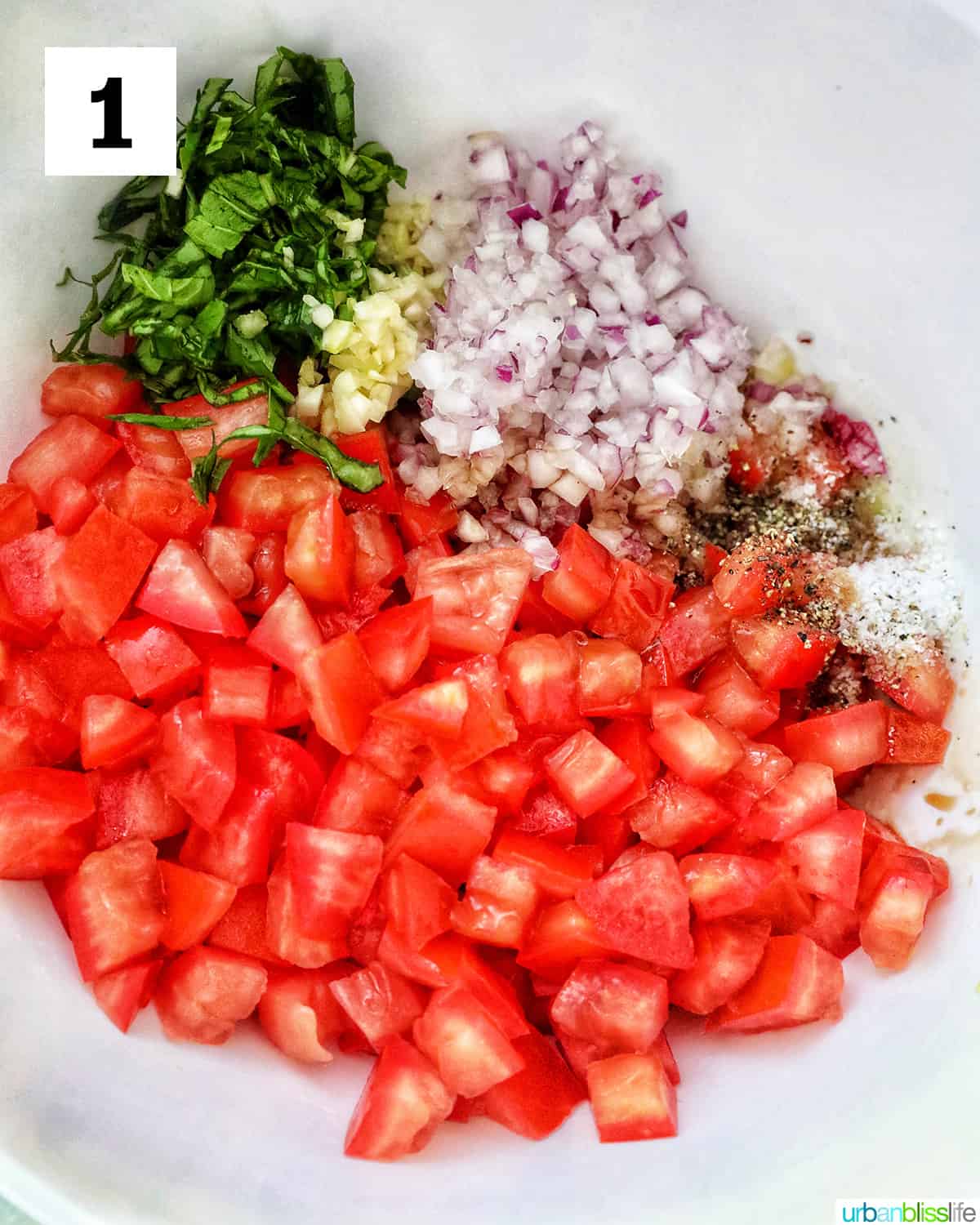 bowl of diced roma tomatoes, sliced basil leaves, minced garlic and red onions.