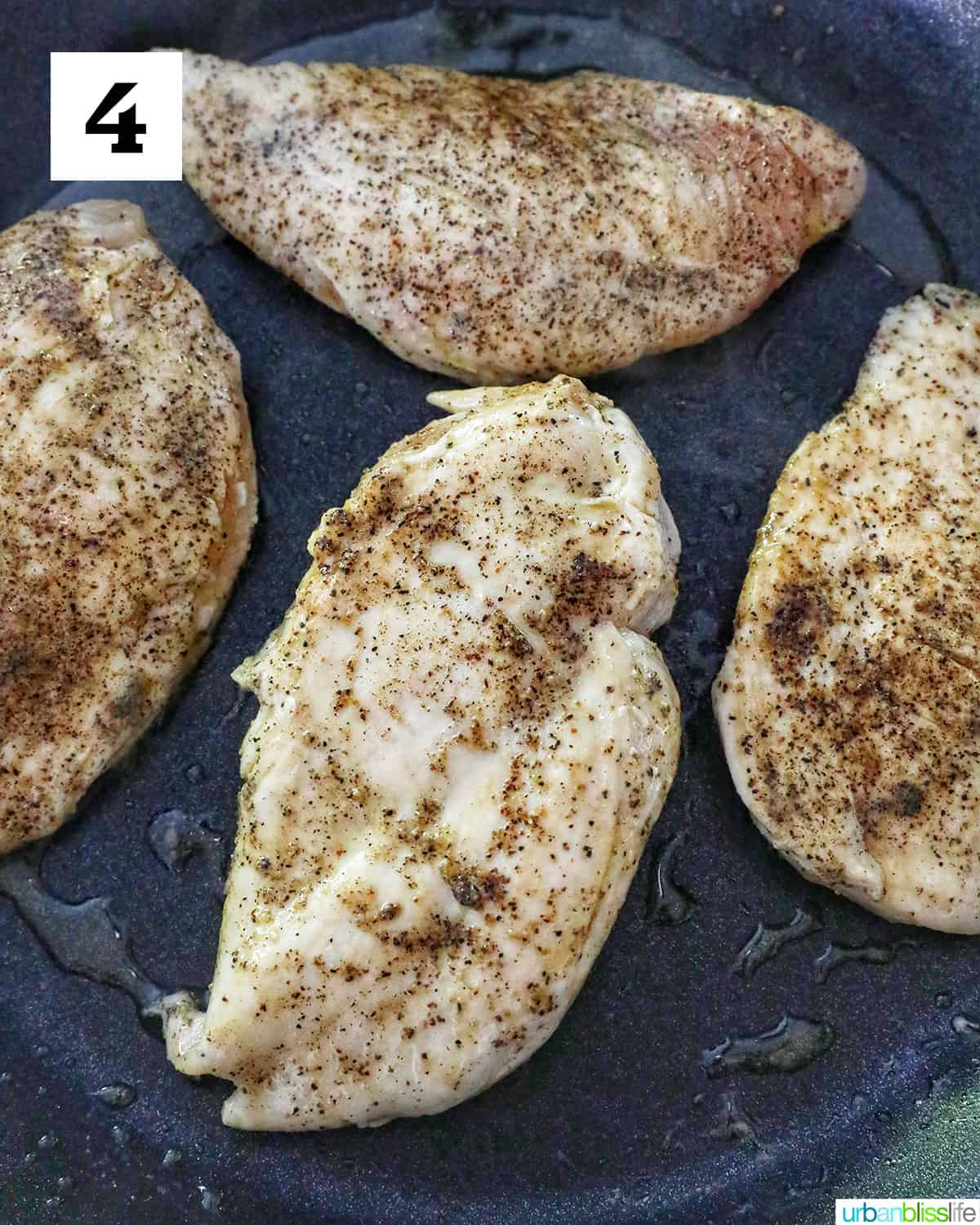 four chicken breasts seasoned with salt and pepper in a skillet.