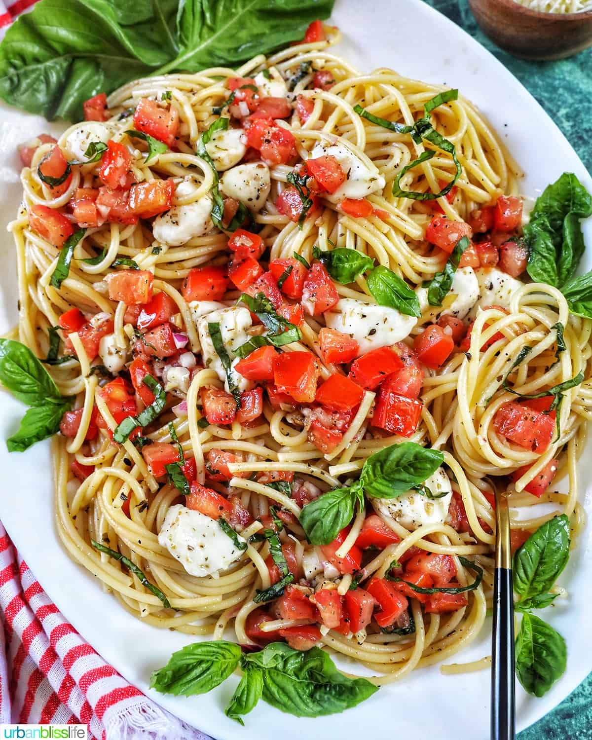 bruschetta pasta with tomatoes, mozzarella, basil in a large white serving platter.