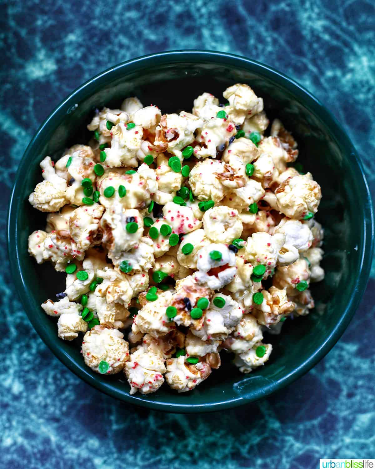 big bowl of Christmas popcorn on a green table.