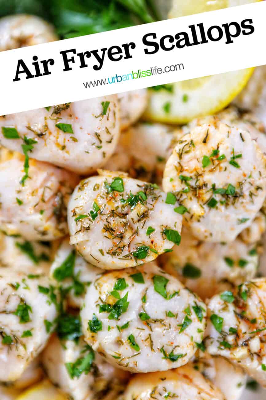 several cooked scallops topped with herbs and garlic, with lemon slices and parsley, on a white plate with text overlay.