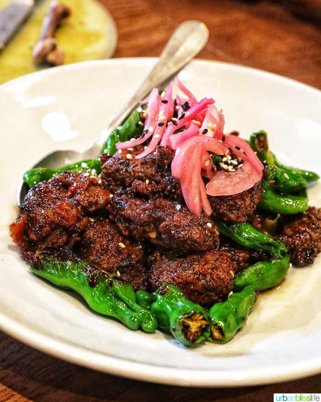 ginger beef with pickled onions and peppers on a white plate.