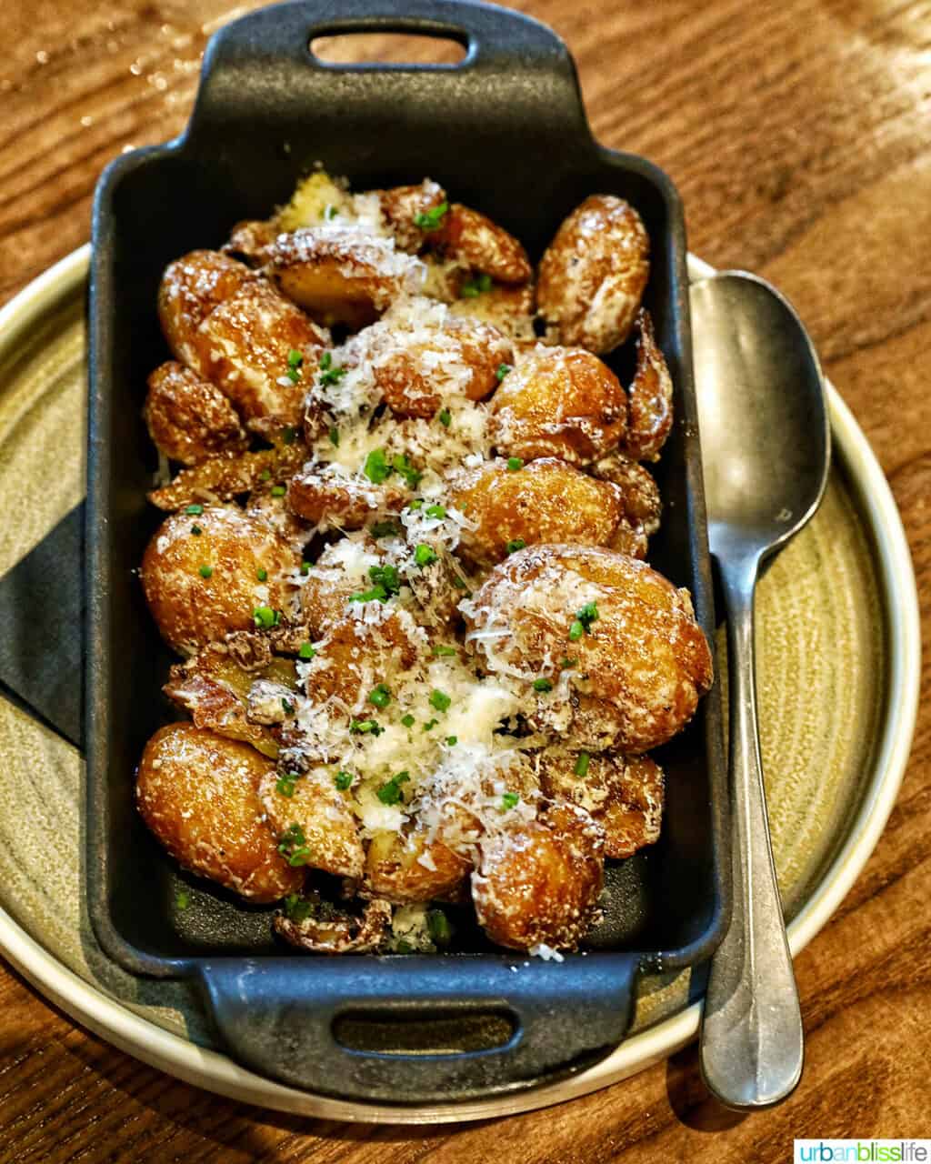 parmesan truffle potatoes in a cast iron serving plate with spoon.