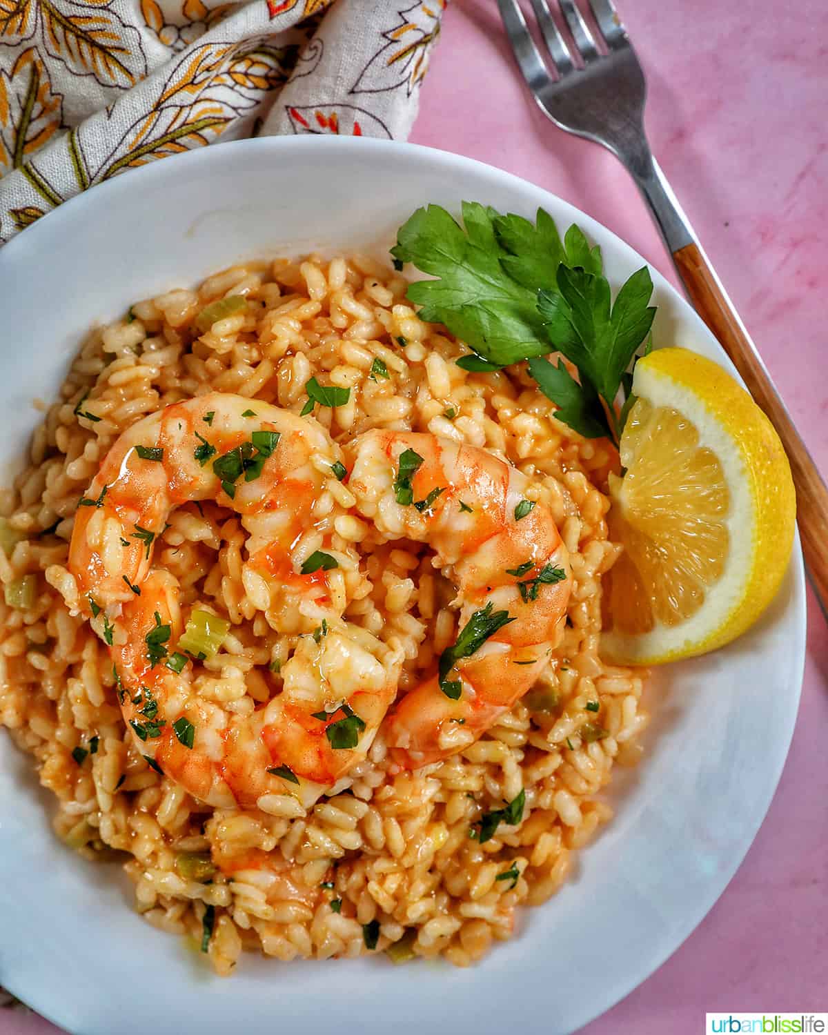 white bowl full of shrimp risotto, with a side of lemon wedge and parsley.