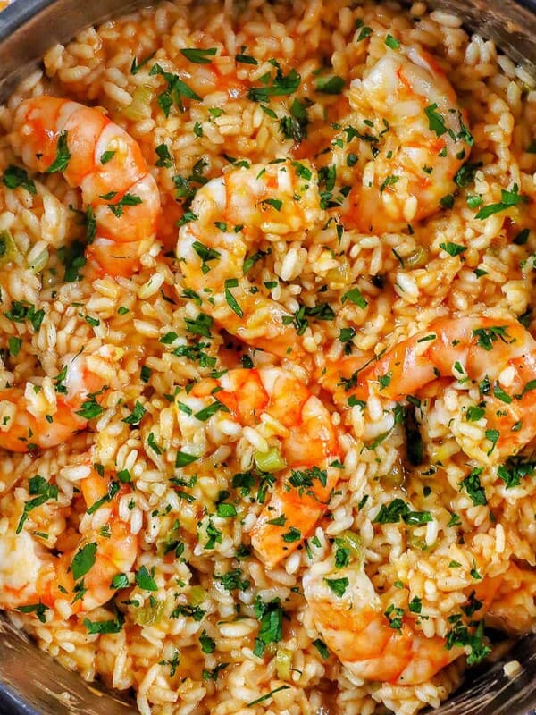 risotto with prawns and herbs in a stainless steel pan.
