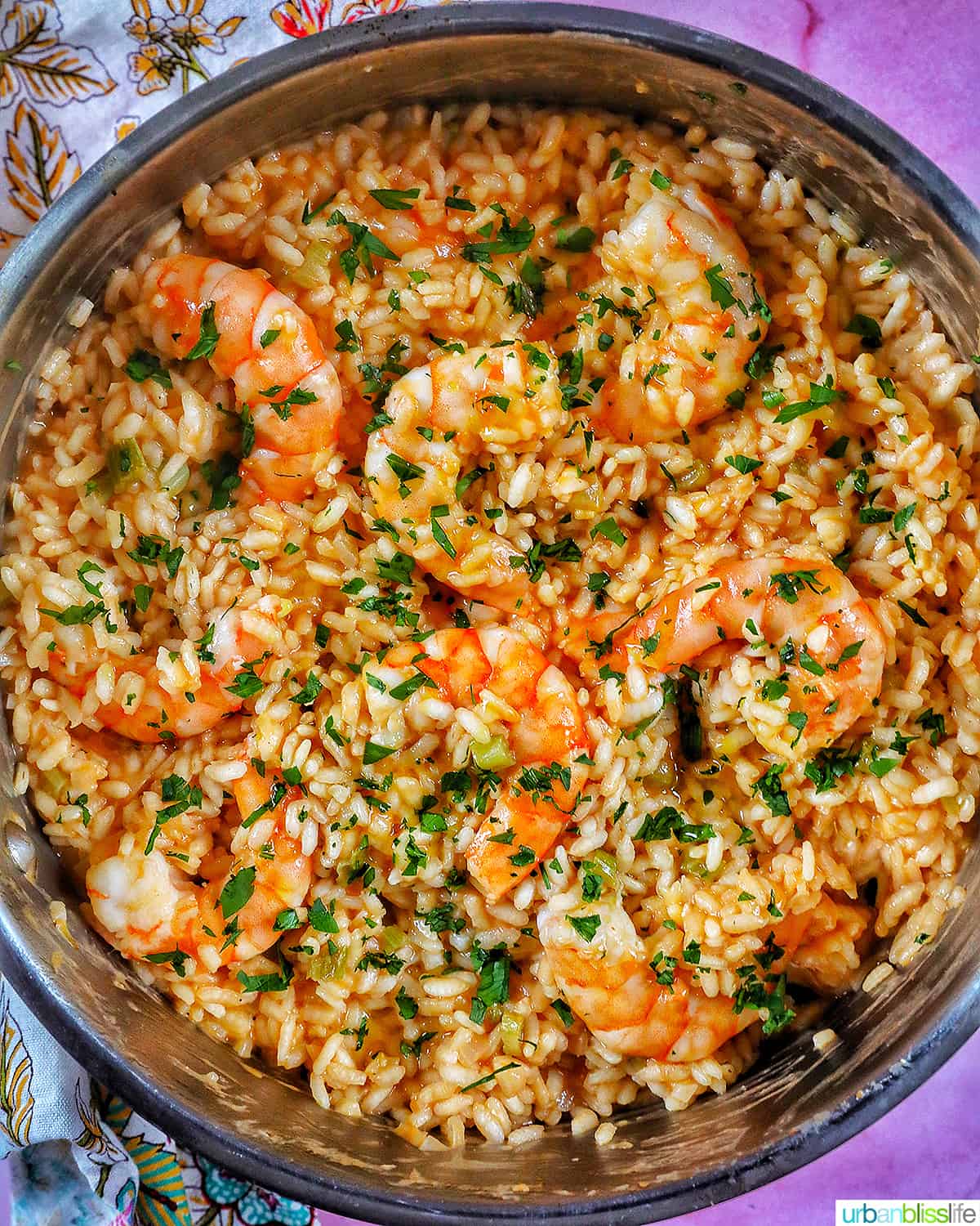 risotto with prawns and herbs in a stainless steel pan.