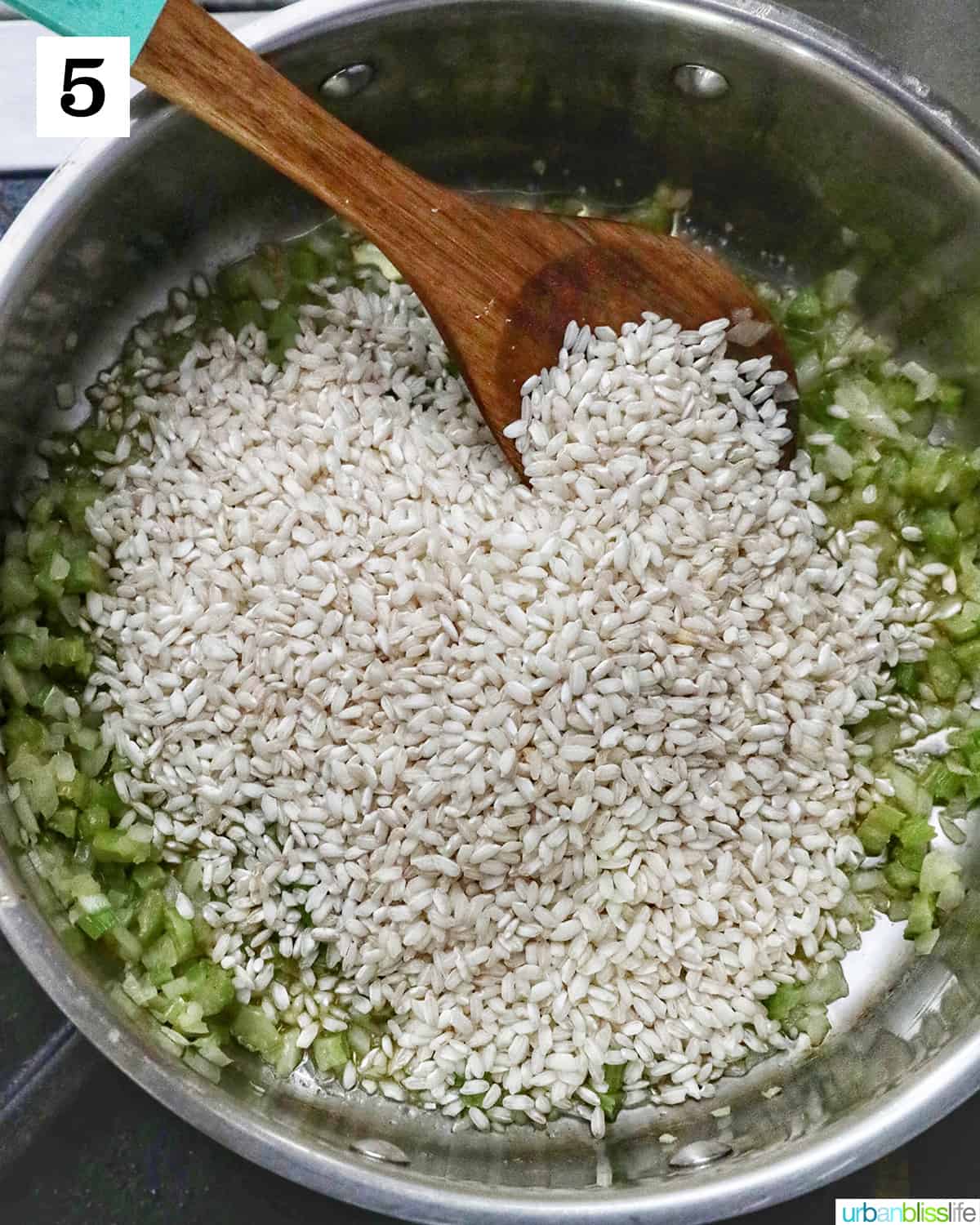 adding rice to onions, garlic, celery in a pot and stirring with a wooden spoon.
