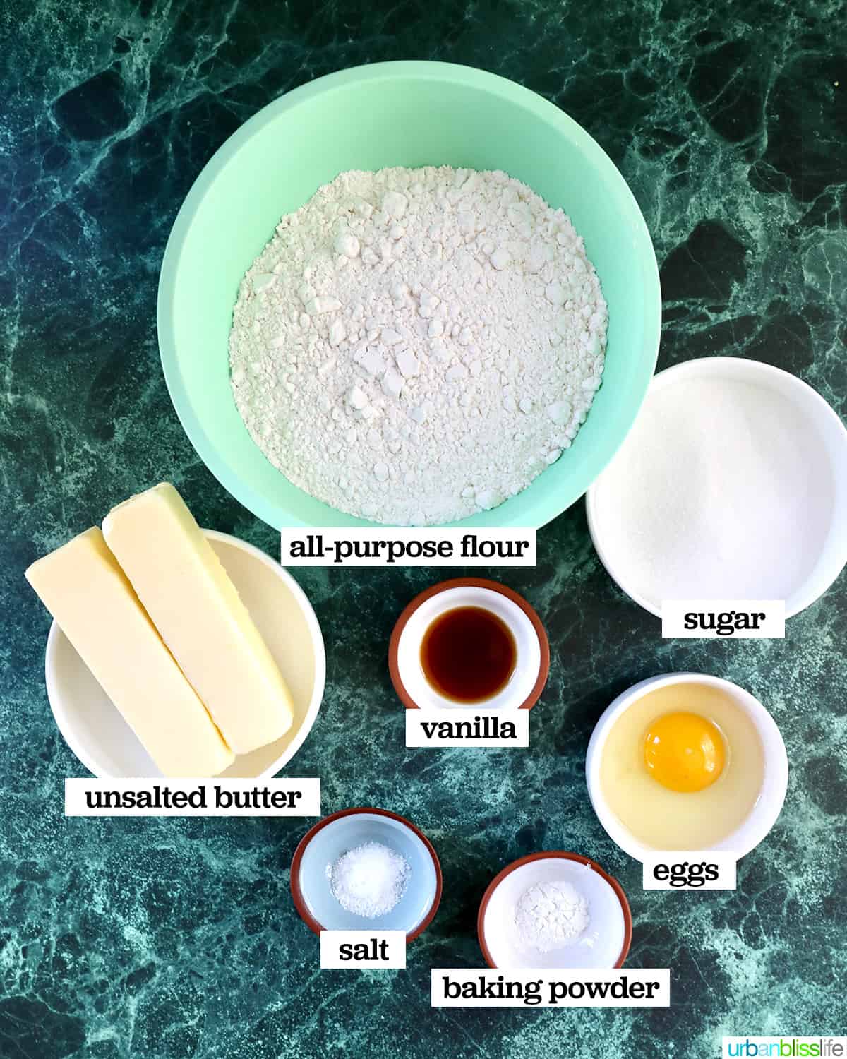 bowls of ingredients to make sugar cookies on a green marble table.