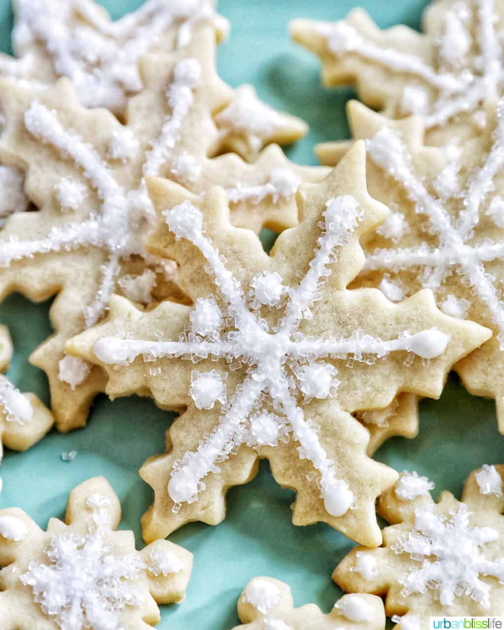 plate full of snowflake sugar cookies decorated with royal icing and decorator sugar.