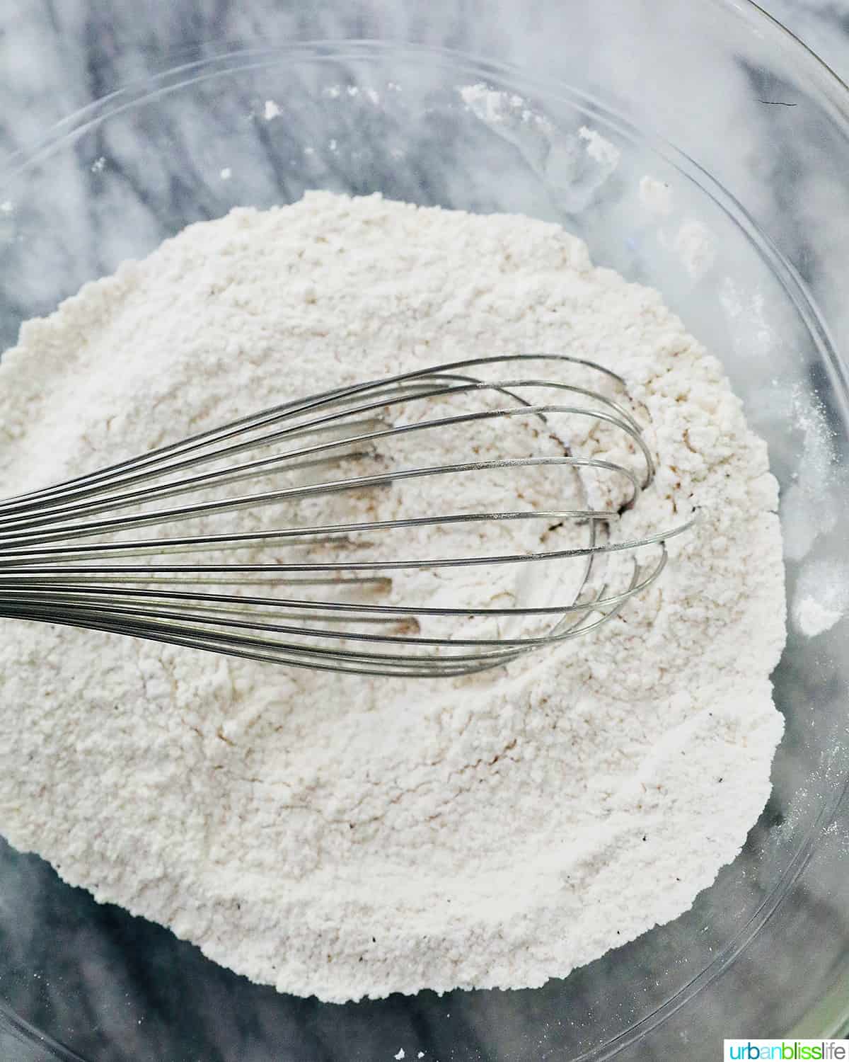 whisking together dry ingredients in a clear glass bowl.