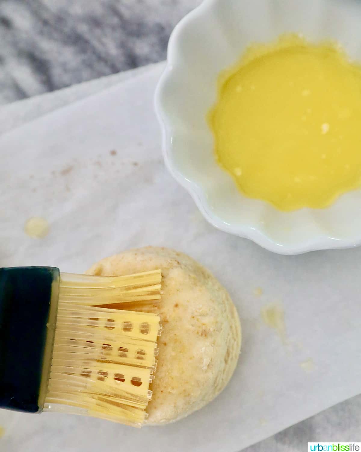 pastry brush brushing melted butter onto an air fried biscuit.