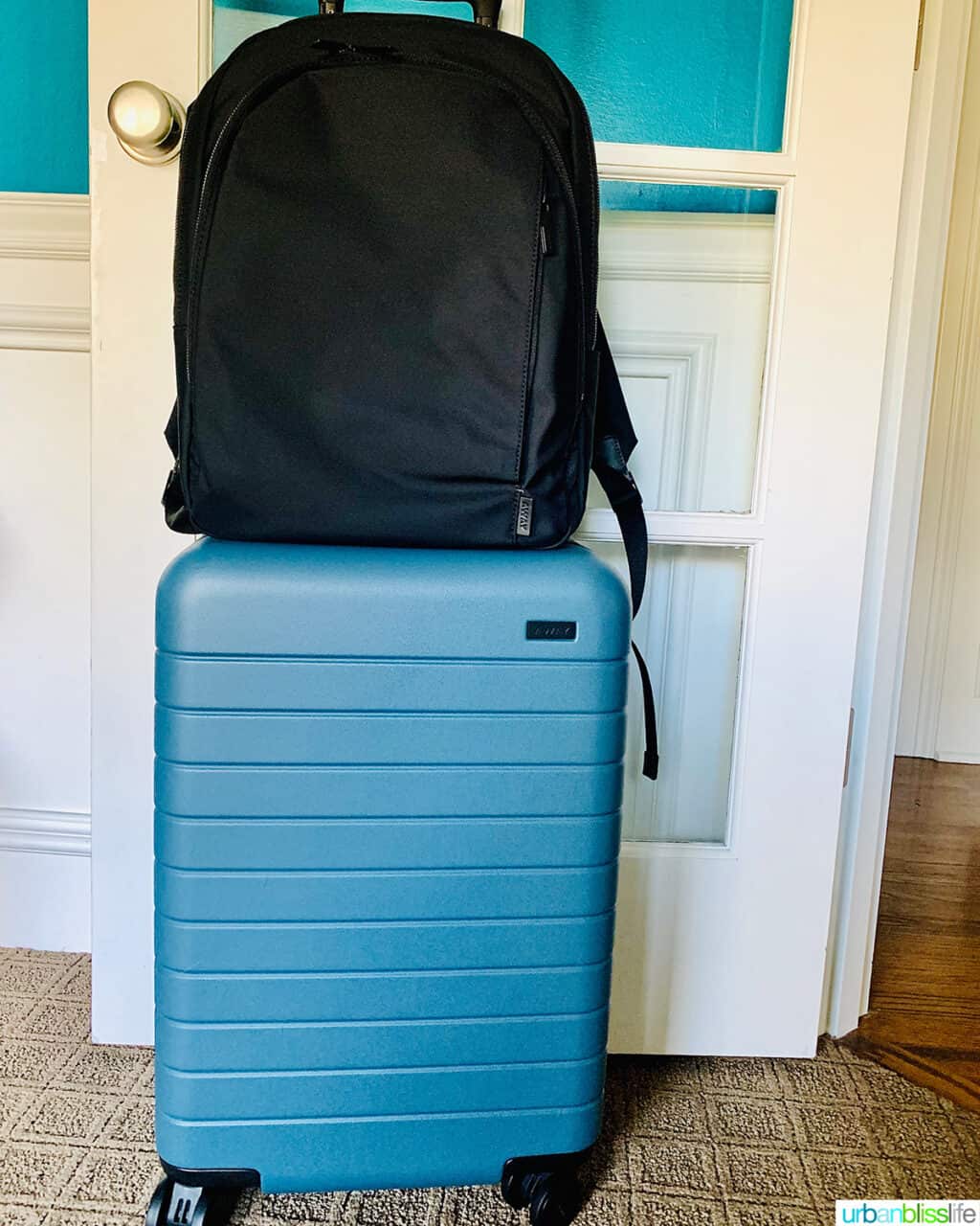 black backpack on top of blue Away luggage.