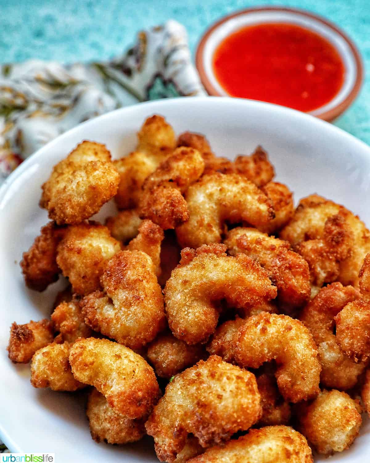 air fryer popcorn shrimp on a plate with side of cocktail sauce.