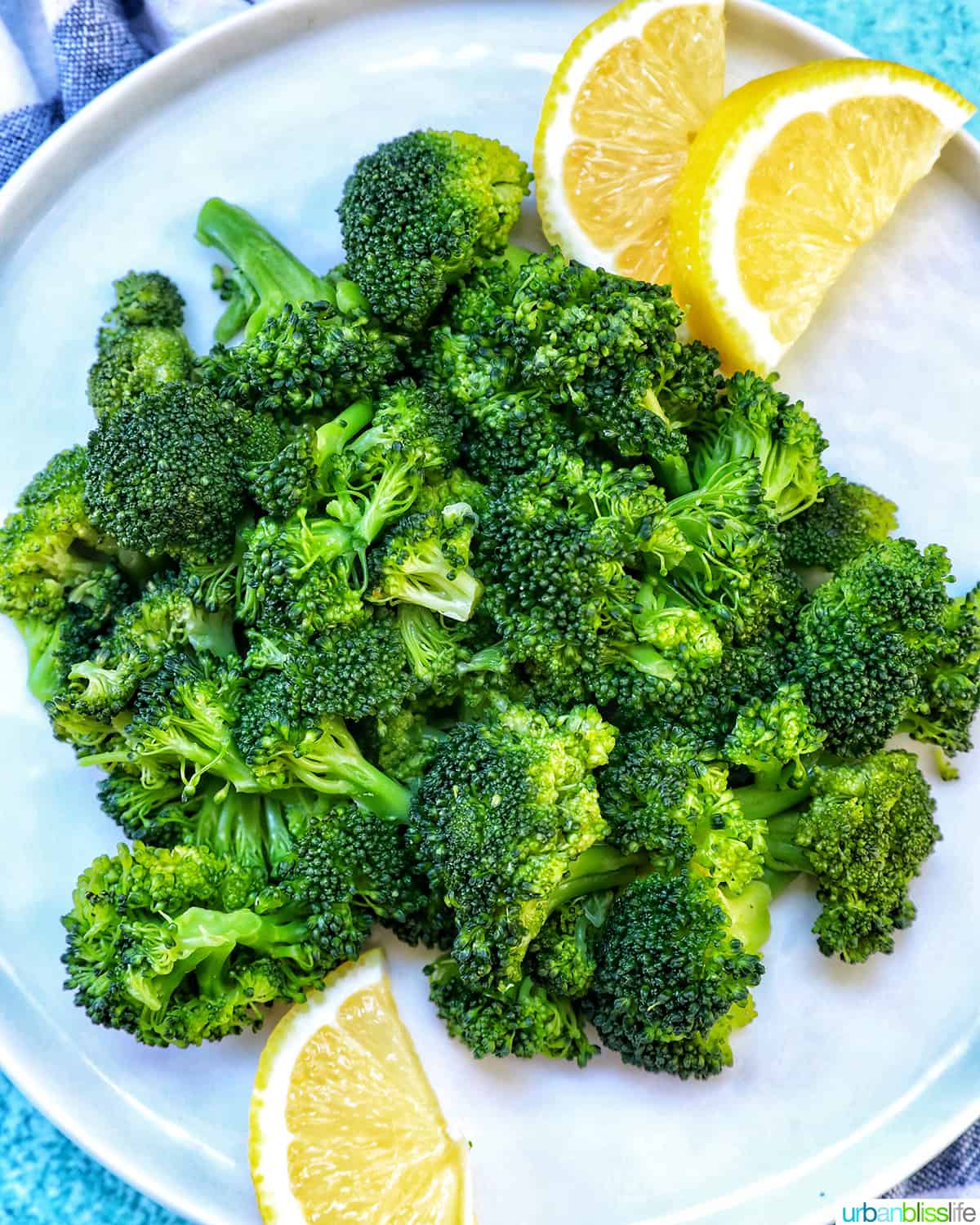 pressure cooked broccoli in a plate with lemon wedges.