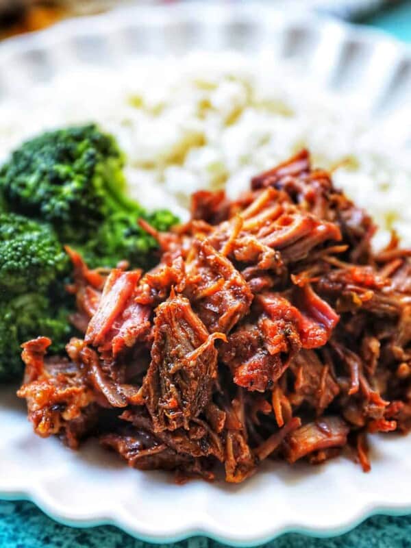 Mexican shredded beef on a plate with rice and broccoli.