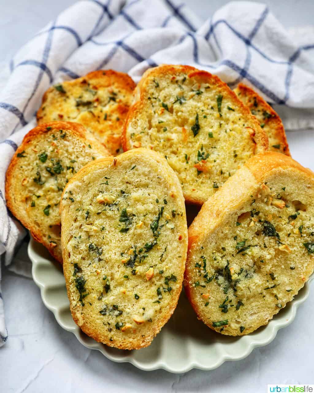 plate full of sliced garlic bread with kitchen towel.