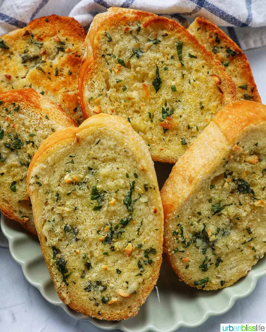 plate full of sliced garlic bread with kitchen towel.