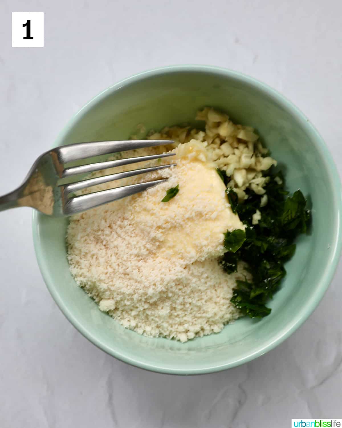 bowl full of ingredients to make a garlic butter spread, with fork on top.