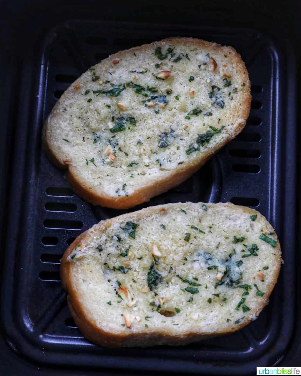two slices of garlic bread in an air fryer basket.