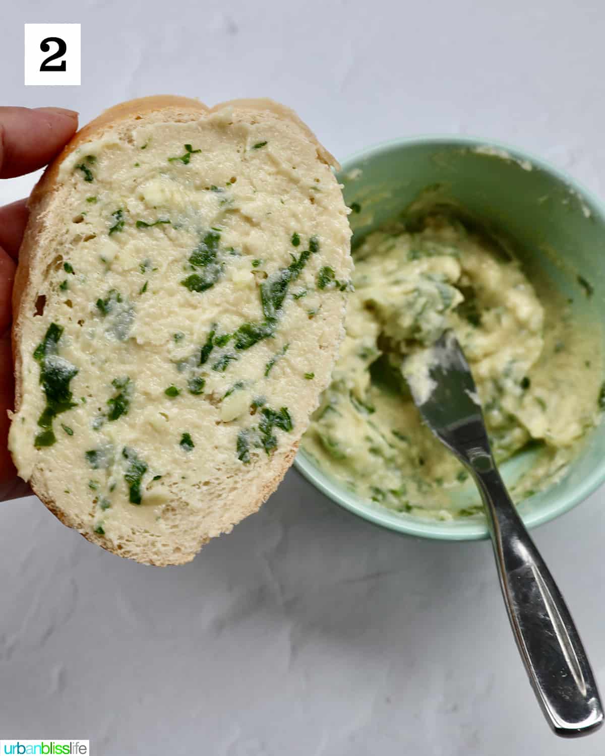 spreading garlic butter spread onto a garlic bread slice.