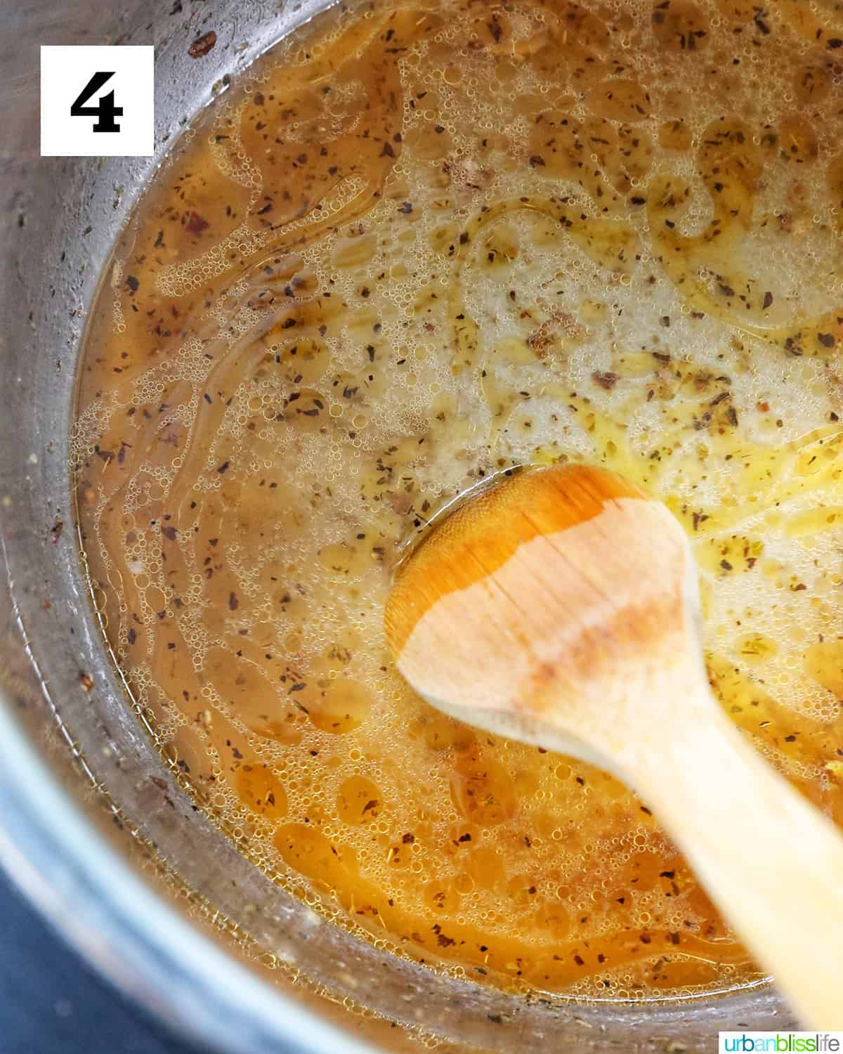 deglazing instant pot with chicken broth and a wooden spoon.