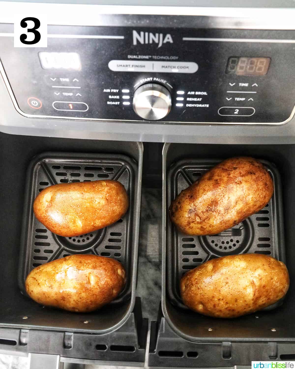 four baked potatoes in a Ninja Foodi airfryer.