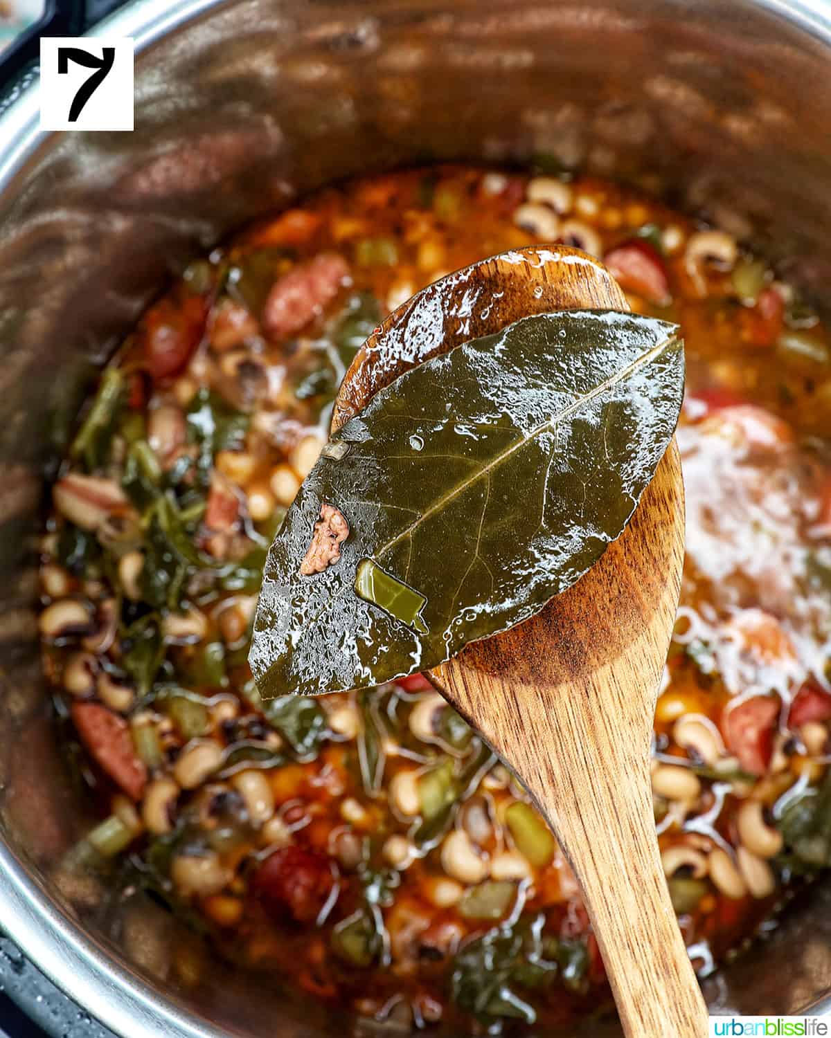 bay leaves on a wooden spoon above an Instant Pot of black eyed peas.
