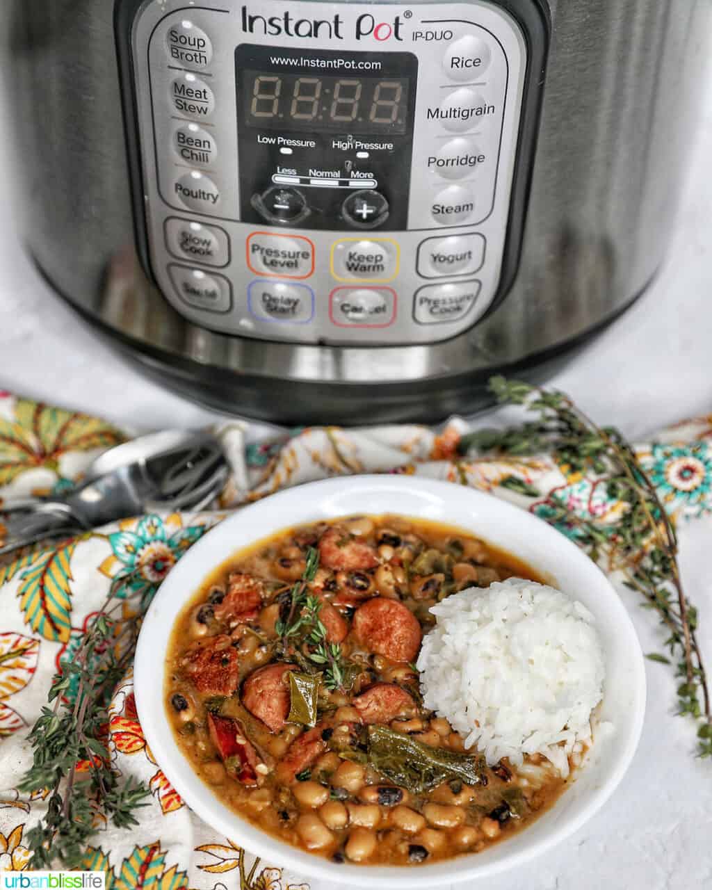 Instant Pot black eyes peas with scoop of white rice in a white bowl in front of an Instant Pot.