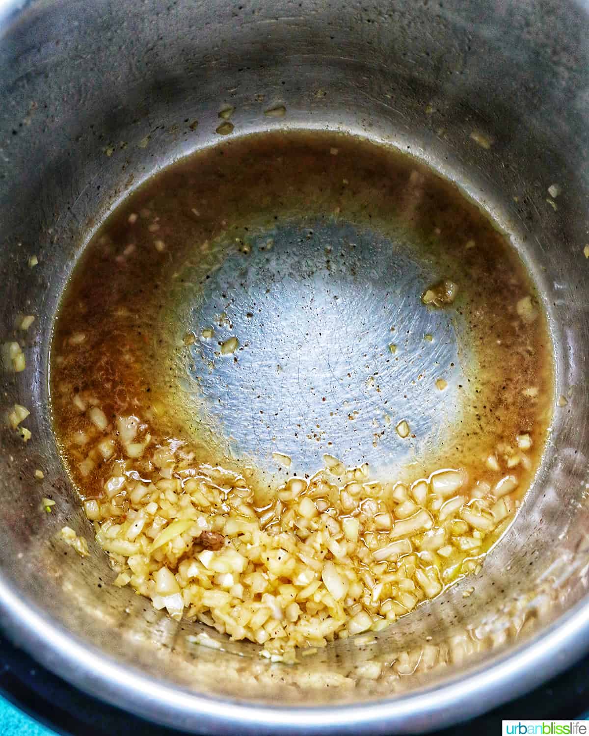 deglazing the Instant Pot with some broth with sauteed onions and garlic in the pot.